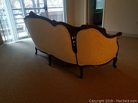 Rear view showing carved wooden frame and fabric back