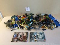 Front view of loose Lego Bionicle pieces with two instruction manuals for Skrall and Strakk sets laid flat.