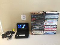 Sony portable DVD player in use playing a DVD, showing screen and included adapters with the stack of 47 DVDs beside it.