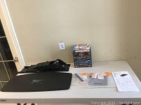 Full view of table with keyboard tray parts, mouse pad, instructions, and stack of Blu-Ray and DVD movies