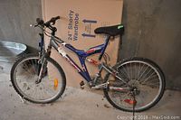 Side view of blue and silver Dymo mountain bike showing frame, wheels, saddle, and rear shock absorber.