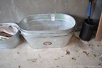 Five oval metal ice buckets stacked together showing their size and shape.