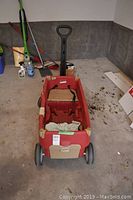 Front view of Step 2 red children's wagon showing handle, seating area with seat belts, and front wheels.