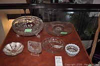 Large vintage crystal footed bowl and surrounding glass platters and containers on table