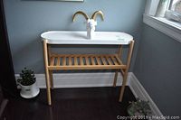 Ikea plant stand with metal top and wooden frame, white goat head sculpture on top