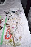 Full view of costume jewelry including pearl, bead and chain necklaces and bracelets alongside Fossil and Storm watches and FitBit.