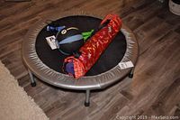 Mini trampoline with fitness equipment arranged on top including the ball weight, dumbbells, jump rope and yoga mat in bag