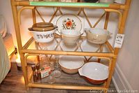 Shelf with vintage Pyrex mixing bowls and casserole dishes along with salt and pepper shakers and glass condiment jars.