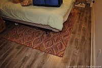 Area rug in basement under bed frame, showing full width and pattern detail