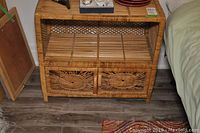Front view of the vintage wicker storage cabinet showing open top shelf and double door compartment below.