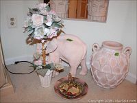 Photo showing large terra cotta lattice style water jug, terra cotta momma elephant, faux floral topiary, Bradford Exchange prayer heart plate and Portuguese stoneware plate, and small brass picture stand arranged on floor.
