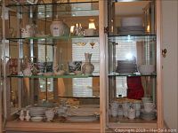 Wide view of glass-front cabinet showing the entire display of china and serveware pieces arranged on shelves.