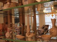 Glass cabinet shelf showing Lenox porcelain bud vases, small candy bowl, small swan figurine, Portmeirion mugs with coasters, ceramic bunny, and glass basket.