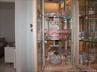 Glass cabinet showing Waterford crystal, pink shell motif serving dishes, and stemware