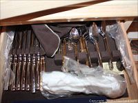 Drawer with Yamasaki flatware pieces arranged in fabric holder, including knives, forks, spoons