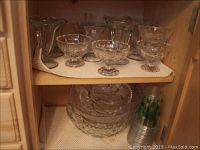 Photo of six ice cream sundae bowls, footed ice cream bowls, punch bowl, serving bowls and plastic cups on shelves.