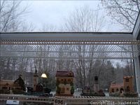 Wide view showing five resin miniature houses arranged in a row on a shelf near a window, including different shapes and sizes with details like chimneys and detailed rooftops.