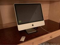 Front view of white iMac with aluminum stand on wood shelf