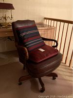 Full view of vintage Sam Moore desk chair with leather upholstery and carved wooden arms, seated cushion in striped fabric included.