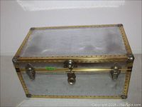 Silver-tone metal faced trunk with brass-tone riveted edged and lock clasp on front