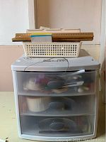 Full view of white Sterilite plastic drawers with rulers and basket on top.