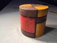 Side view of the colorful pottery jar showing the segmented orange, yellow and brown design.