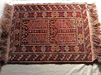 Full view of the small rectangular prayer mat showing geometric and floral patterns with fringes on the shorter edges.