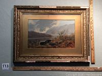 Full view of the framed oil on board landscape painting showing gold-toned decorative frame and protective glass with age wear visible on frame.