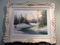 Framed oil painting depicting winter landscape with snow, trees and river, signed Anna