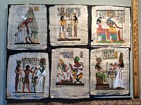 Photo of six hand-painted papyrus sheets mounted on cork board showing various Egyptian kings with hieroglyphics