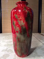 Full front view of red and green flambe vase on fabric background