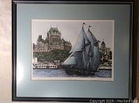 Framed art print showing Bluenose II sailing ship against Quebec cityscape, hung on wall.