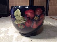 Front exterior view showing hand-painted red and green floral design on cobalt blue glazed bowl