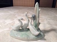 Side angle showing group of four ducks and vertical weed detail on greenish base.