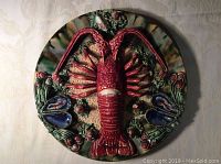 Front view of large ceramic plate with raised lobster and mussels in vibrant colors, showing detailed relief and color glazing.