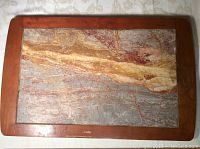 Full view of the antique cutting board with stone slab and walnut frame on a tablecloth.