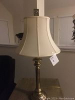 Photo of a 30-inch tall table lamp with brass base and cream fabric shade, showing entire lamp for condition and style assessment.
