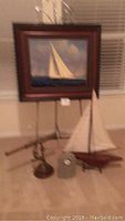 Blurry image of framed sailboat oil painting, brass spyglass, model sailboat, concrete clock