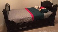 Full side view of Napoleon Era ebonized oak day bed with custom fitted bedding and sheets folded on top