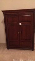 Closed view of Ethan Allen computer cabinet showing paneled double doors with brass knobs and crown molding along the top edge.