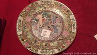 Top-down view of the detailed, large circular Asian decorative plate showcasing central figures and floral border.