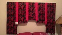 Full front view of the red and black dragon fabric headboard mounted on wall above bed.