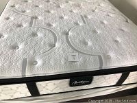 Photo of white quilted queen hybrid mattress on metal bed frame with box spring visible underneath
