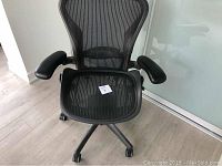 Front view of black Herman Miller Aeron mesh office chair showing seat, back, armrests and caster base