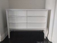 Front view of white four-drawer office cabinet or dresser showing clean lines and drawer configuration.