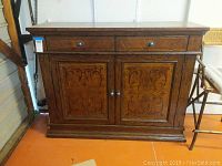 Front view of wooden buffet-credenza with two drawers and closed cabinet doors, showing decorative wood panel work and metal knobs