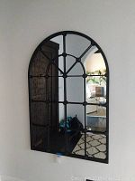 Front view of the large arched wall mirror showing its grid-style black metal frame and clear glass.
