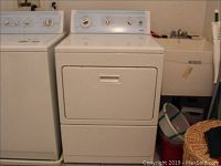 White Kenmore Elite dryer with front-loading door and control panel with dials and push-to-start button. Shows marks and soiling.