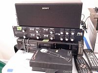 Front view of the stacked Sony SSCN109 speaker on PVS EX35 audio processor unit, with Sony stereo cassette deck TC-WE305 below and Nippon America wireless microphone box on top of cassette deck, including multiple remote controls to the right.