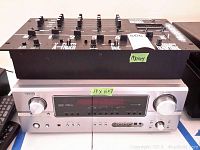 Numark DM1600X mixer on top of Denon receiver showing front panel and control knobs.